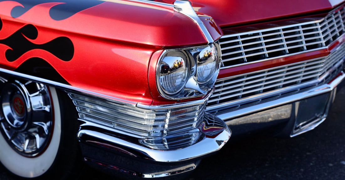 A view of the front of a vintage muscle car. The car has flames painted on the front of it near the headlight.